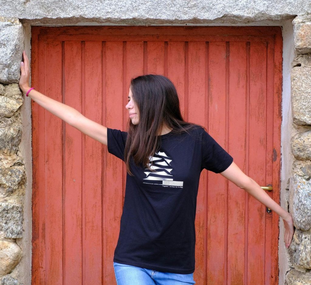 Chica con camiseta negra estampada con el edificio La Pagoda, frente a una puerta roja