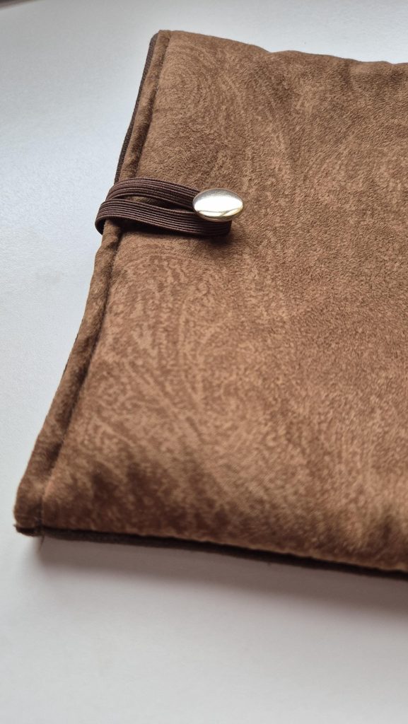 Funda para libro de tela marrón con efecto ante y goma de cierre con botón