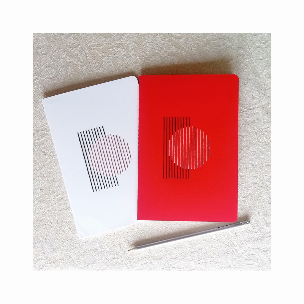Dos libretas A5 bordadas a mano con un círculo, una blanca y una roja